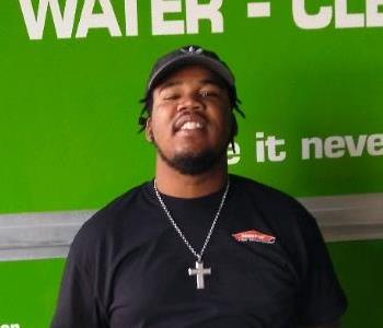 male crew member standing in front of a SERVPRO green truck.